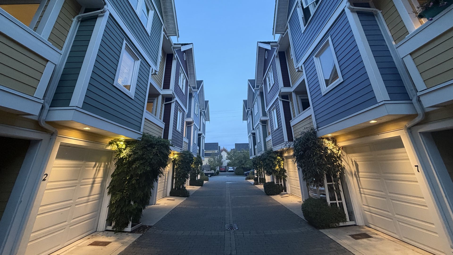 Freshly renovated townhouse row with lit garages along a paved lane